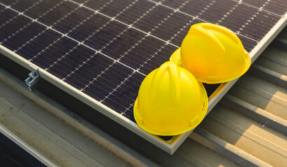 Engineer helmet on blue photovoltaic solar panels at solar cell farm, Clean ecological electricity with sunset, Renewable energy, Alternative electricity source, Concept of sustainable resources